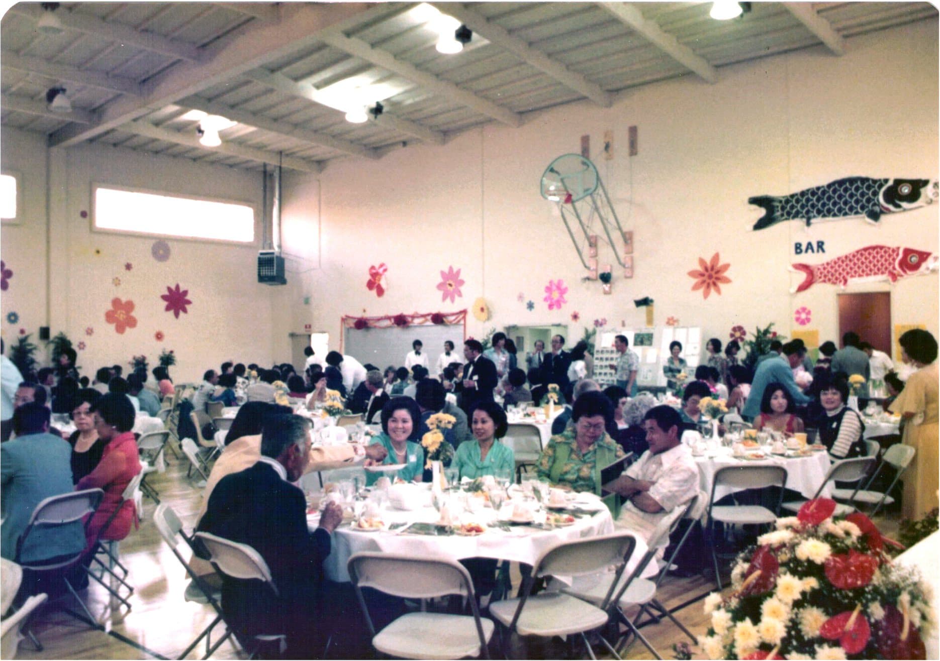 The hall full of guests at the 1977 new building dedication, hung with koinobori