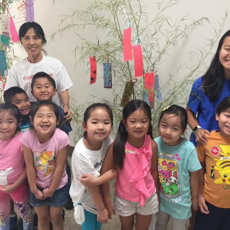 Students beside a tanabata bamboo hung with paper wishes