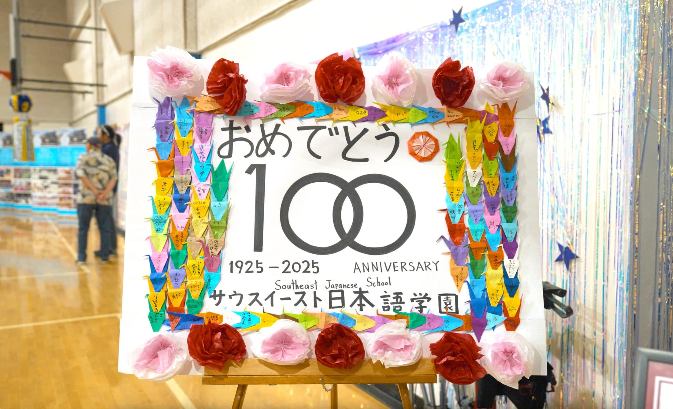 The hand-decorated “Omedetō 100” sign, framed in paper flowers and folded cranes, from the 100th anniversary celebration