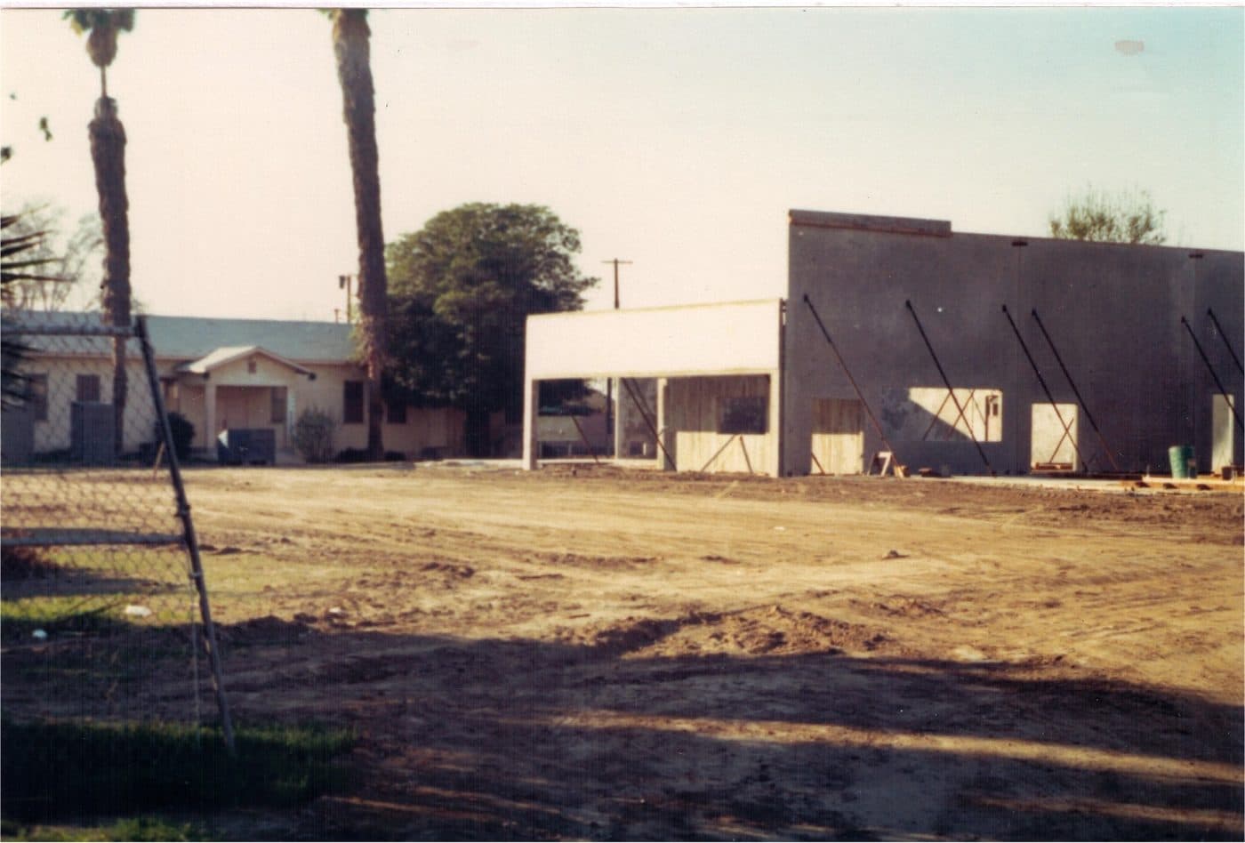 The walls of the new gymnasium under construction in 1977, braced with timber, beside the old school