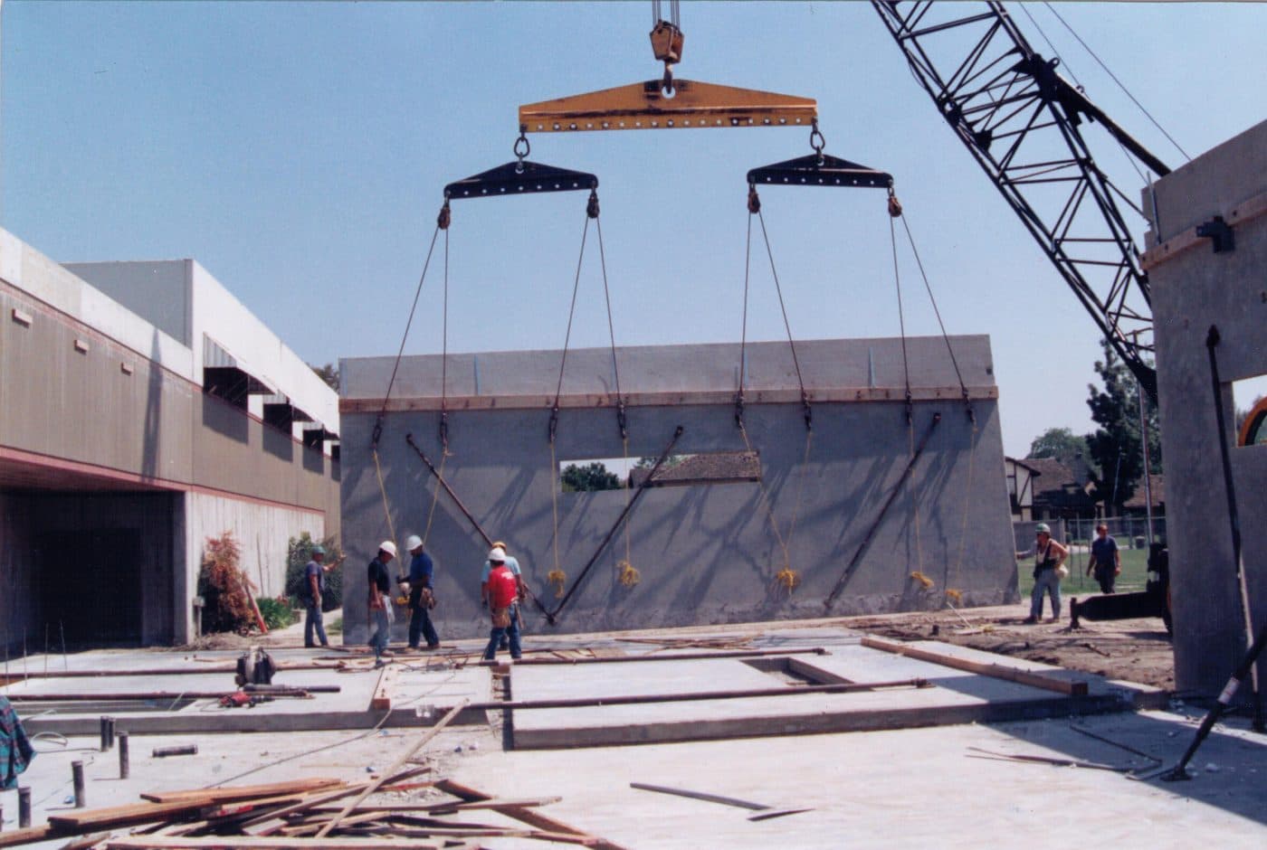 A crane raising a concrete wall panel for the 1994 annex while workers watch
