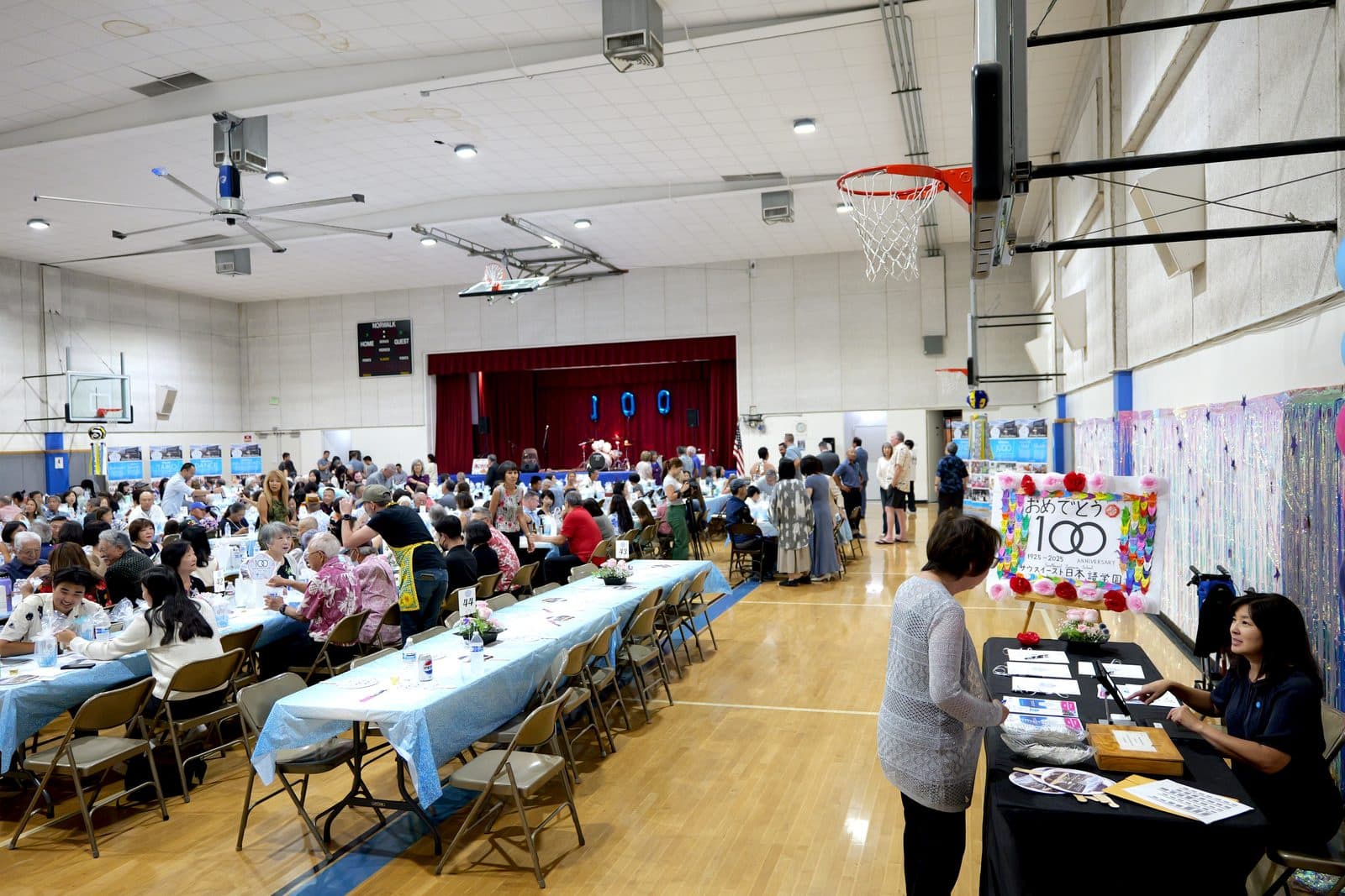 The gymnasium filled with long tables and guests at the 100th anniversary celebration