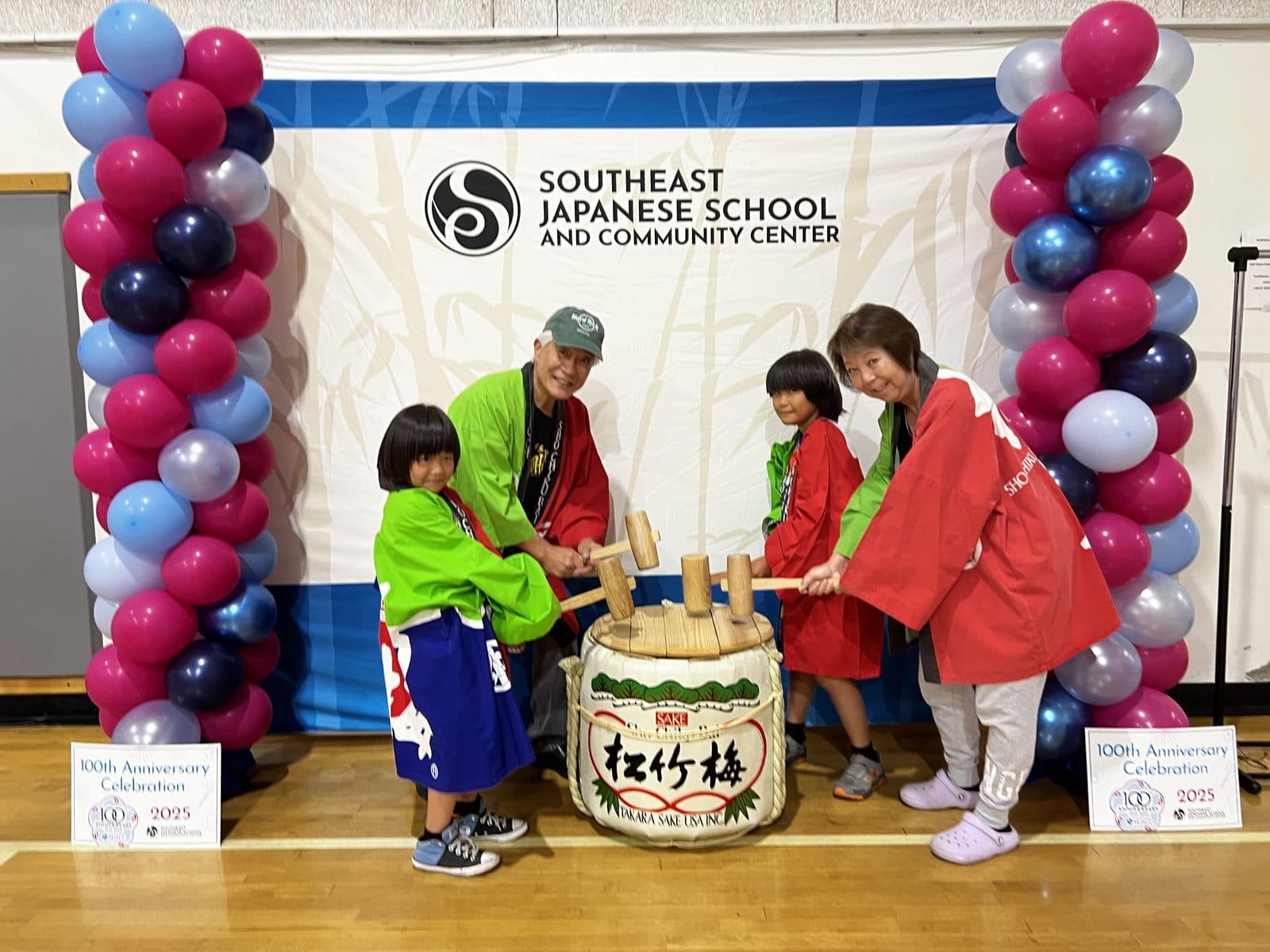 Children in happi coats breaking open a sake barrel at the photo booth