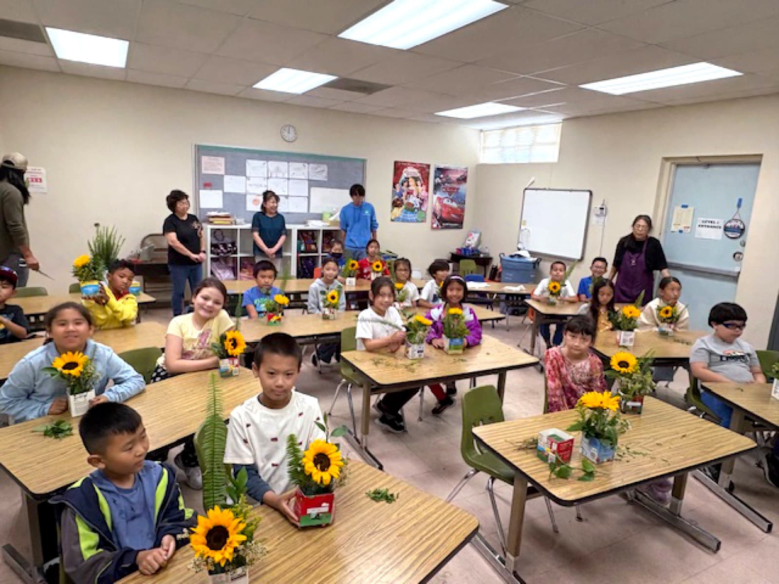 A classroom of students at their desks with the flower arrangements they made