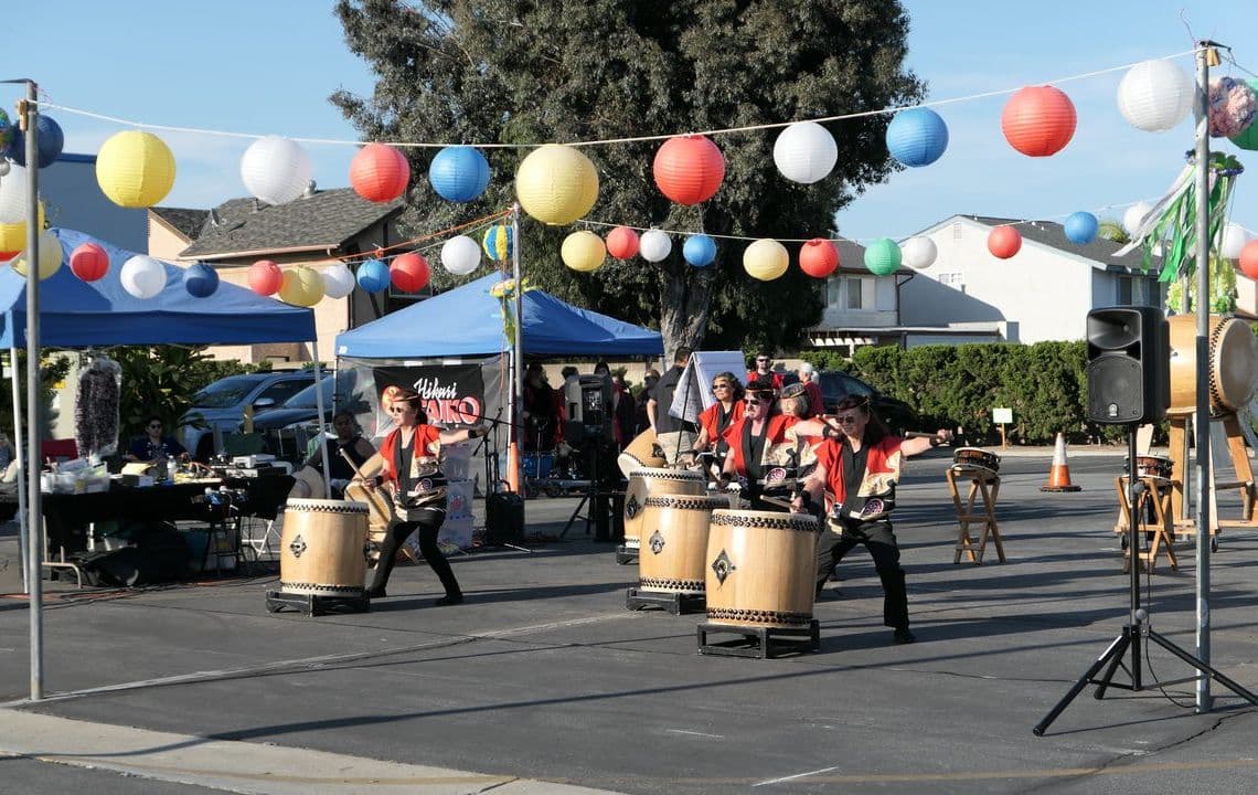 Taiko drummers mid-performance beneath paper lanterns at the summer festival